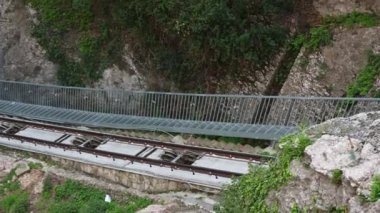 Monistrol de Montserrat, Barcelona - İspanya 03-27-2024: Demiryolu raylarının üzerinden geçerek sağdan sola doğru vadiye giden panorama. Tırmanma araçları açıkça görülüyor.