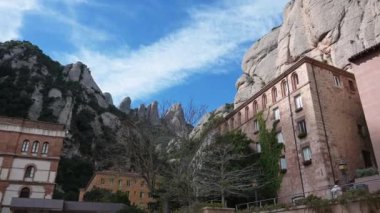 Monistrol de Montserrat, Barcelona - İspanya 03-27-2024: Montserrat dağ sırasının üzerinden, yoldan geçenlerin kapılara yürüdüğü manastıra. Manastır dağda çok güzel duruyor.