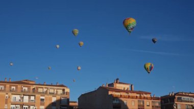 Guadix, Granada - İspanya 01-25-2024: Birçok sıcak hava balonu aynı anda mavi, bulutsuz gökyüzüne yükseliyor, sabah güneşi altında yüzerek.