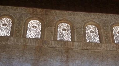 Granada, Granada - İspanya - 01-27-2024: Alhambra 'da bir koridorun karşısında, gün ışığıyla yıkanan, karmaşık bir şekilde işlenmiş cephe ve pencerelerin üzerinde.