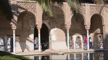 Granada, Granada - İspanya 01-27-2024: Alhambra 'nın süslü cephesinin manzarası, ziyaretçiler su havzasında geziniyor. Dalgalar nazikçe sanatsal görünüme yansıyor.