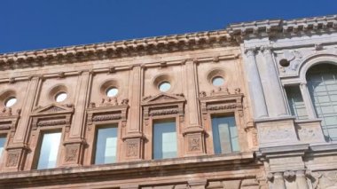 Granada, Granada - İspanya - 01-27-2024: Charles V Sarayı 'nın ön cephesinde geniş, simetrik taşlardan yapılmış bir tava. Ön cephe mavi bir gökyüzünün altında güneş ışığında parlıyor.