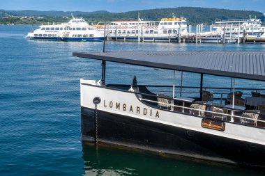 Arona, Piemont - Italy - 07-04-2024: Lombardia excursion ship docked at Arona pier on Lake Maggiore, with other boats in the background. clipart