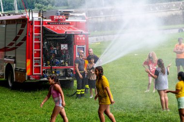 Angera, Lombardei - İtalya - 07-02-2024: İtfaiyecilerle birlikte itfaiye kamyonu çocukları su jetleriyle tazeleyecek