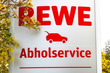 Brieselang, Brandenburg - Almanya - 03-29-2022: Rewe kamyonet servisi için çarpıcı bir kırmızı-beyaz işareti, koleksiyonu ve perakende hizmetlerini sembolize ediyor.
