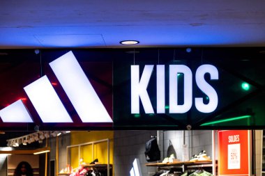 Casablanca, Casablanca-Settat - Fas - 07-27-2024: Aydınlatılmış Adidas Çocukları koyu renk bir perakende mağazasında parlayan, çocuk bölümünün altını çizen imzalar.