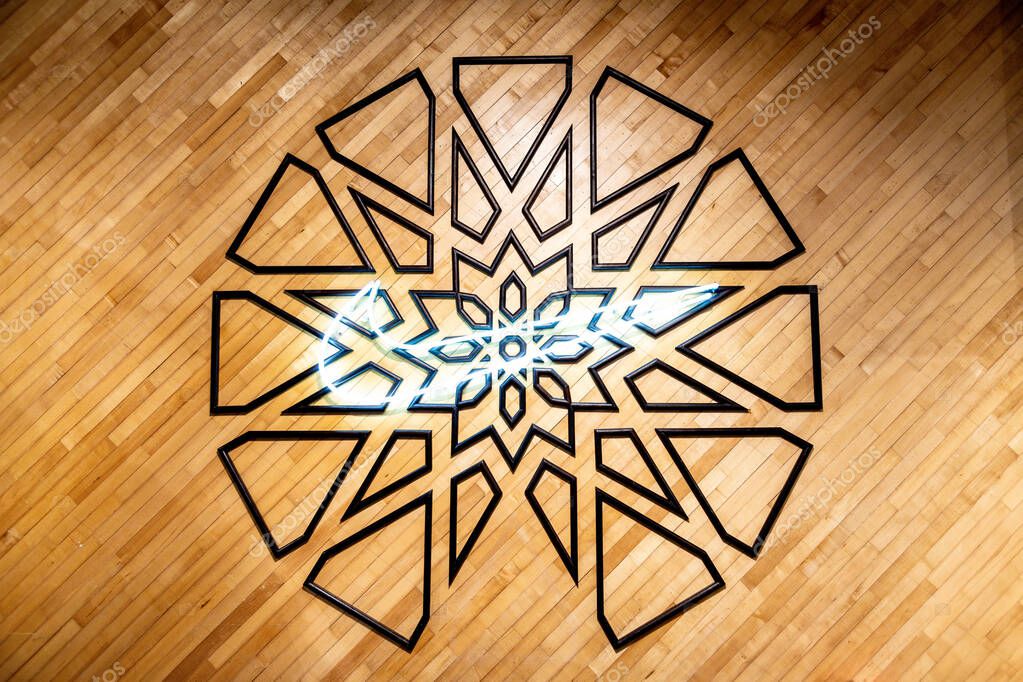 Casablanca, Casablanca-Settat - Morocco - 07-27-2024: A glowing Nike logo on a wooden wall with a geometric pattern in the background.