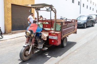 Agadir, Souss-Massa - Fas - 07-31-2024: Üç tekerlekli bir motosiklet, yükleme platformu, Docker marka, yüklü, Agadir, Fas 'ta bir yolda