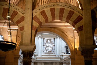 Cordoba, Cordoba - İspanya - 04-08-2024: Mezquita-Katedral de Cordoba 'nın kırmızı ve beyaz kemerlerinden dini bir figürün heykeline doğru bakın.