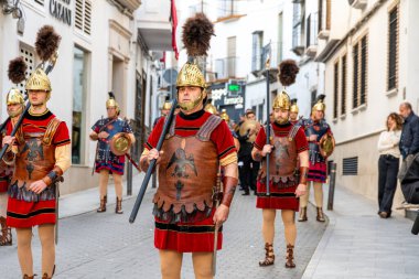 Castro del Rio, Cordoba - İspanya - 03-24-2024: Deri zırhlı ve altın kasklı Romalı askerler Semana Santa Paskalya alayı sırasında sokaklarda yürüyorlar.