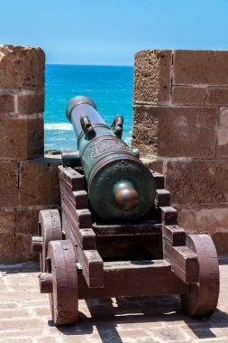 Essaouira 'daki bir kale duvarından deniz manzaralı ahşap taşıma üzerinde antik bir topun yakın çekimi..