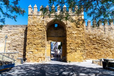 Cordoba, Cordoba - İspanya - 04-08-2024: Cordoba 'da eski kale duvarlarıyla çevrili taş kemerli bir geçit, girişte güneş ışığı gölgeleri var.