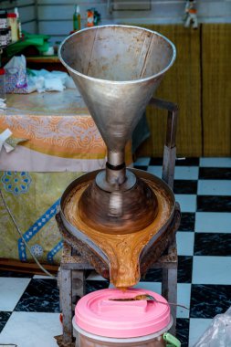 Cordoba, Cordoba - İspanya - 04-08-2024: Argan yağı üretmek için metal huni, plastik bir kaba akan kahverengi madde.