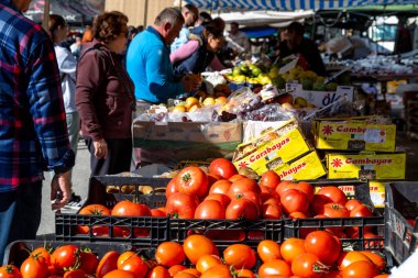 Guadix, Granada - İspanya - 01-24-2024: Arka planda ziyaretçilerin olduğu bir açık hava pazarında taze sandık domates, elma ve armut.