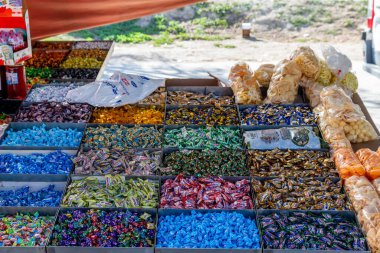 Guadix, Granada - İspanya - 01-24-2024: Renklere göre sınıflandırılmış birden fazla kutuda bir dizi şekerin yer aldığı canlı bir pazar sahnesi.