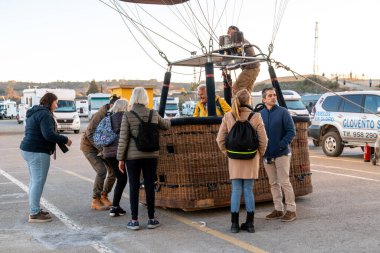 Guadix, Granada - İspanya - 01-24-2024: Yolcular birkaç sıcak hava balonu ile çevrili balon sepetine biniyorlar. Bir grup insan yolculuk için hazırlanıyor..