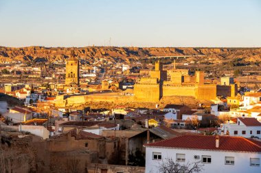 Guadix, Granada - İspanya - 01-24-2024: Mağara evleri ve modern binalarla çevrili, akşam güneşiyle aydınlanan bir ortaçağ Fas kalesi olan Guadix Alcazaba 'ya yakın çekim.