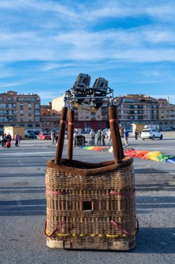 Guadix, Granada - İspanya - 01-24-2024: Açık bir alanda sıcak hava balonu sepeti; arka planda insanlar ve binalar tarafından çevrelenmiş brülör ve detaylar görünür.