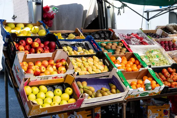 Guadix, Granada - İspanya - 01-24-2024: Yeşil bir gölgelik altında taze elma, armut, portakal ve çeşitli meyvelerle dolu market tezgahı.