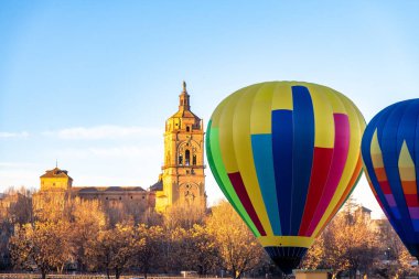 Guadix, İspanya 'daki Katedral' in ön cephesini renkli sıcak hava balonları dolduruyor. Uzun sarı, mavi ve kırmızı bir balon sonbahar ağaçları arasında belirir..