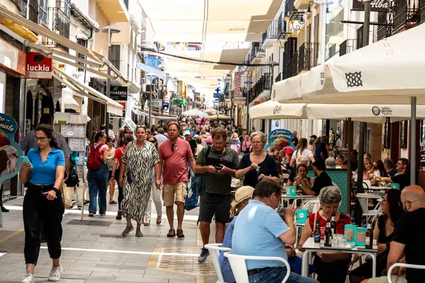 Ronda, Malaga - İspanya - 06-04-2024: İspanya 'nın Ronda kentinde kafe ve gölgeli güneş yelkenleri altında alışveriş yapan insanlarla dolu kalabalık bir yaya bölgesi.