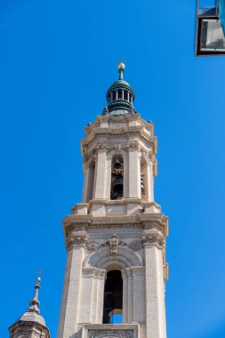 Basilica del Pilar 'daki çan kulesine yakın çekim. Barok detaylar, görünür çanlar ve açık mavi gökyüzü altında yeşil kubbe..