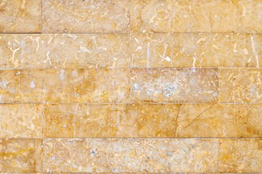 Stone wall made of marble or granite with yellow to brown wear marks and tiny joints between the stones. clipart