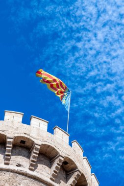 Valencia 'da Torres de Quart, bir ortaçağ kulesi. Çırpılmış bir yapısı var. Valencia bayrağı mavi gökyüzüne doğru dalgalanmakta..