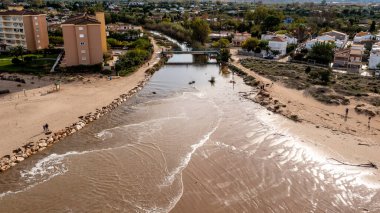 Denia, Alicante - İspanya - 11-13-2024: Kum plajları ve apartman binaları arasında akan sakin nehir manzarası.