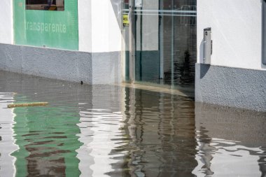 Tavira, Algarve - Portekiz - 09-18-2024: Binanın girişi suyla dolu, çevredeki yapıları yansıtıyor.