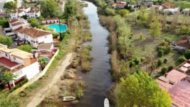 Denia, Alicante - İspanya - 11-13-2024: Fırtına ve sağanak yağmurdan sonra: Sel basmış bir nehrin havadan görünüşü, yüzen botlar, kısmi kıyı şeridi selleri ve nehir kıyısı boyunca evler.