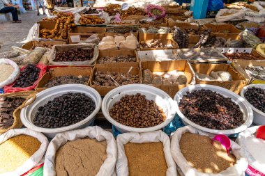 A market stall with a variety of dried foods such as figs, dates, and spices, beautifully displayed in baskets, bowls, and sacks for sale. clipart