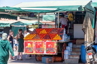 Marrakesch, Marrakesch-Safi - Fas - 08-14-2024: Marakeş 'teki bir pazarda portakal, nar ve limon gibi parlak meyvelerle süslenmiş meyve ve meyve suyu standı.