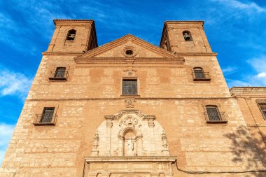 Almagro 'daki San Bartolome Kilisesi' nin ön görüntüsü çan kuleleri, barok ayrıntıları, üçgen geçit ve mavi gökyüzü kontrastı..