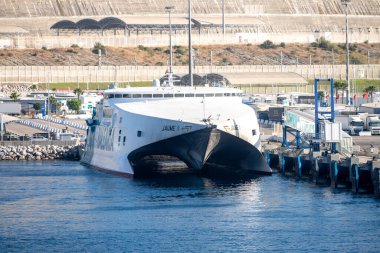 Tanger Med, Fahs-Anjra - Fas - 08-22-2024: Balearia katamaran Jaume I modern bir limana demirledi; görünür altyapı depoları, rampaları ve park edilmiş araçları içeriyor.