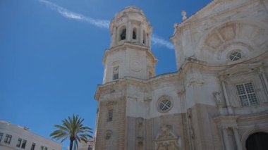 Mavi gökyüzünün altında Cadiz Katedrali 'nin üst kısımlarını tarayın. Katedral aydınlık taştan yapılmıştır ve detaylı mimarisi vardır..