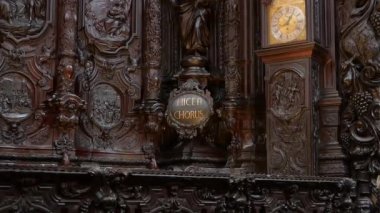 Cordoba, Cordoba - İspanya - 04-08-2024: Mezquita Katedrali korosundaki ayrıntılı ahşap oymalar, altın Hicen Korosu metni, insan sahneleri ve altın saatli bir saat.