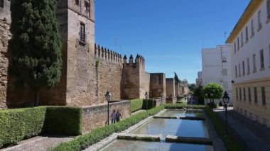 Cordoba, Cordoba - İspanya - 04-09-2024: Parlak mavi bir gökyüzü altında kireç taşı veya kumtaşından yapılmış kuleler, siperler, kapı ve su havzasıyla Cordoba şehir duvarını aşın.