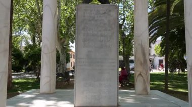 Cordoba, Cordoba - İspanya - 04-09-2024: Monumento a Ibn Zaydun y la princesa Valada üzerinden yukarı doğru çevir; oyma tabletli taş yapı, ağaçlarla çevrili metal eller.