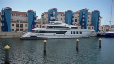 Gibraltar, BOTC - BOTC - 06-03-2024: Lüks yatları, modern liman binaları ve soldan sağa kamera panosu boyunca sakin suları olan Cebelitars marinasının panoramik görüntüsü.