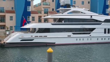 Gibraltar, BOTC - BOTC - 06-03-2024: Lüks yatları, modern liman binaları ve soldan sağa kamera panosu boyunca sakin suları olan Cebelitars marinasının panoramik görüntüsü.