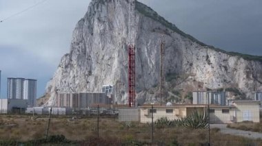 Cebelitarık, BOTC - 06-03-2024: Kablolu mavi gökyüzüne karşı uzun, kırmızı ve beyaz bir radyo direği. Arka plan Cebelitarık Kayası 'nı, binaları ve kurak bitki örtüsünü gösteriyor..