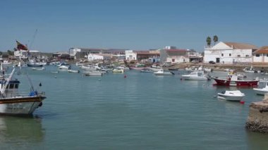 Cristina Adası, Huelva - Portekiz - 09-09-2024: Cristina Adası 'nda küçük balıkçı tekneleri ve sanayi binalarıyla dolu hareketli bir liman. Sakin su, berrak bir gökyüzünün altındaki parlak günü yansıtır..