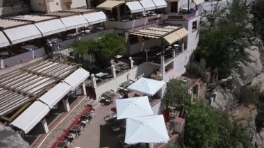 Ronda, Malaga - İspanya - 07-04-2024: İspanya 'nın Ronda kentinde ağaçlar ve binalarla çevrili terasları beyaz şemsiyeler, sandalyeler, masalar ve yakınlardaki uçurumlarla gösteren soldan sağa bir tava.