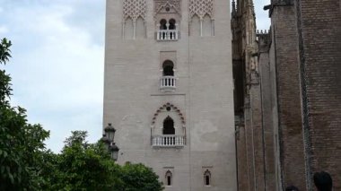 Sevilla, Sevilla - İspanya - 04-19-2024: La Giralda 'dan El Giraldillo heykeline doğru ilerleyin, turistler beklerken, selfie çekerken ve dramatik bulutlar çarpıcı bir zemin oluştururken,.