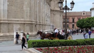 Sevilla, Sevilla - İspanya - 04-19-2024: Seville Katedrallerinin doğu yakası, Palacio Arzobispal, hareket halindeki bir araba ve La Giraldas heykelinin mavi gökyüzünün altındaki tepesi.
