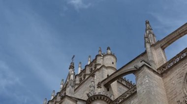 Seville Katedrali 'nin batı cephesinde soldan sağa doğru çevir; siperleri, kemerleri, heykelleri, gül pencerelerini, ba' daki mavi gökyüzünü göster