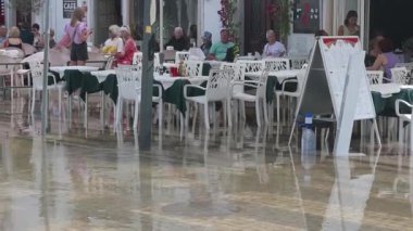 Tavira, Algarve - Portekiz - 09-18-2024: Sel suyunda pek çok sandalyesi olan bir restoranın manzarası; bazı konuklar rögar deliklerinden yükselen suyu görmezden gelerek kuru sandalyelere oturur.