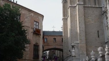 Toledo, Toledo - İspanya - 06-05-2024: Toledo Katedrali 'nin çan kulesine taş bir kemerden çekilen çekim, ayrıntıları, dekorasyonları ve tepede bir hava haçını gösteriyor.