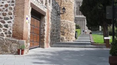 Toledo, Toledo - İspanya - 06-05-2024: İnsanlar Palacio de la Cava 'nın engebeli taş duvarının yanındaki merdivenlerden iniyor, kamera yuvarlak kulelerin arkasında mavi gökyüzü var..